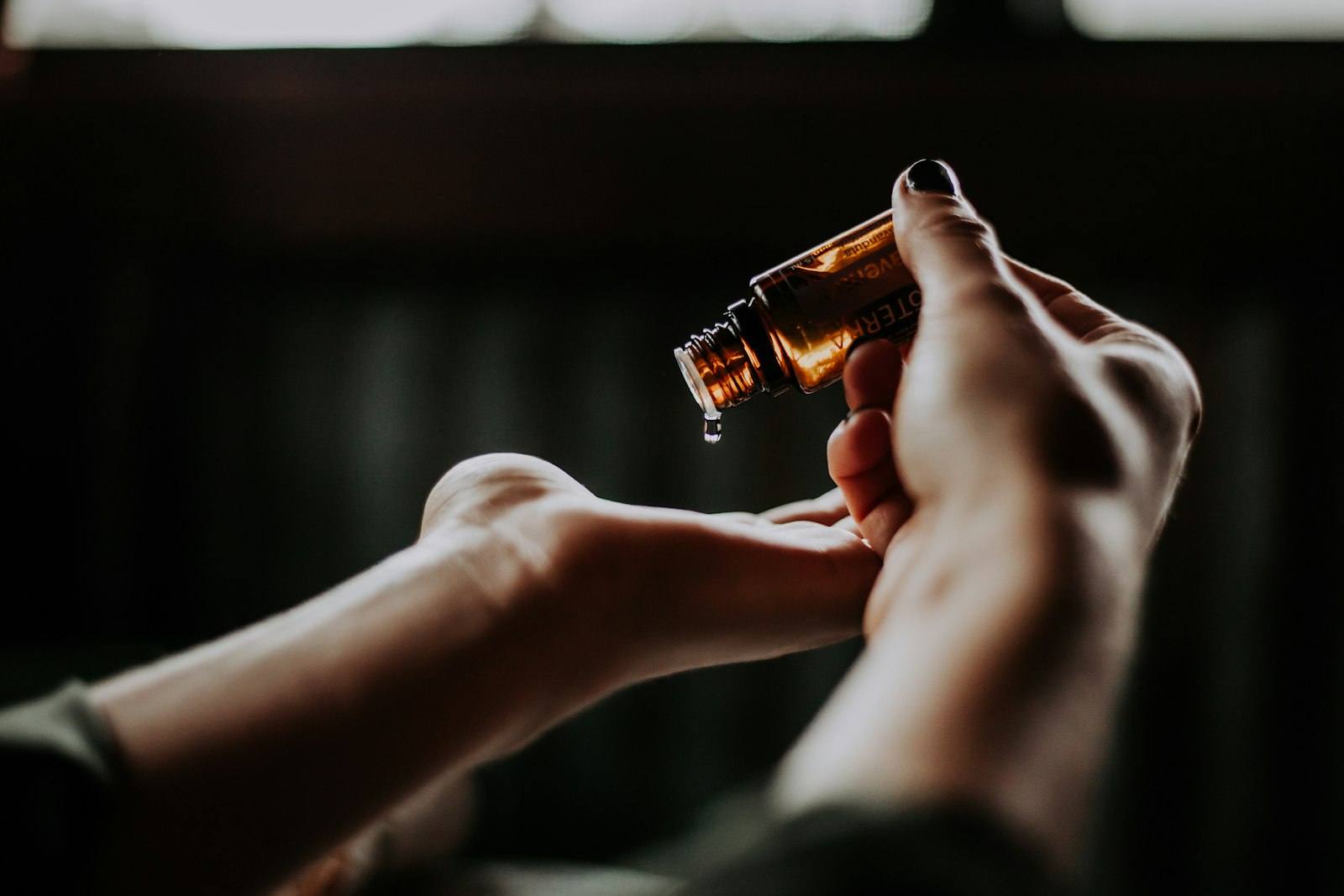 Therapist measuring massage oil from a dropper bottle