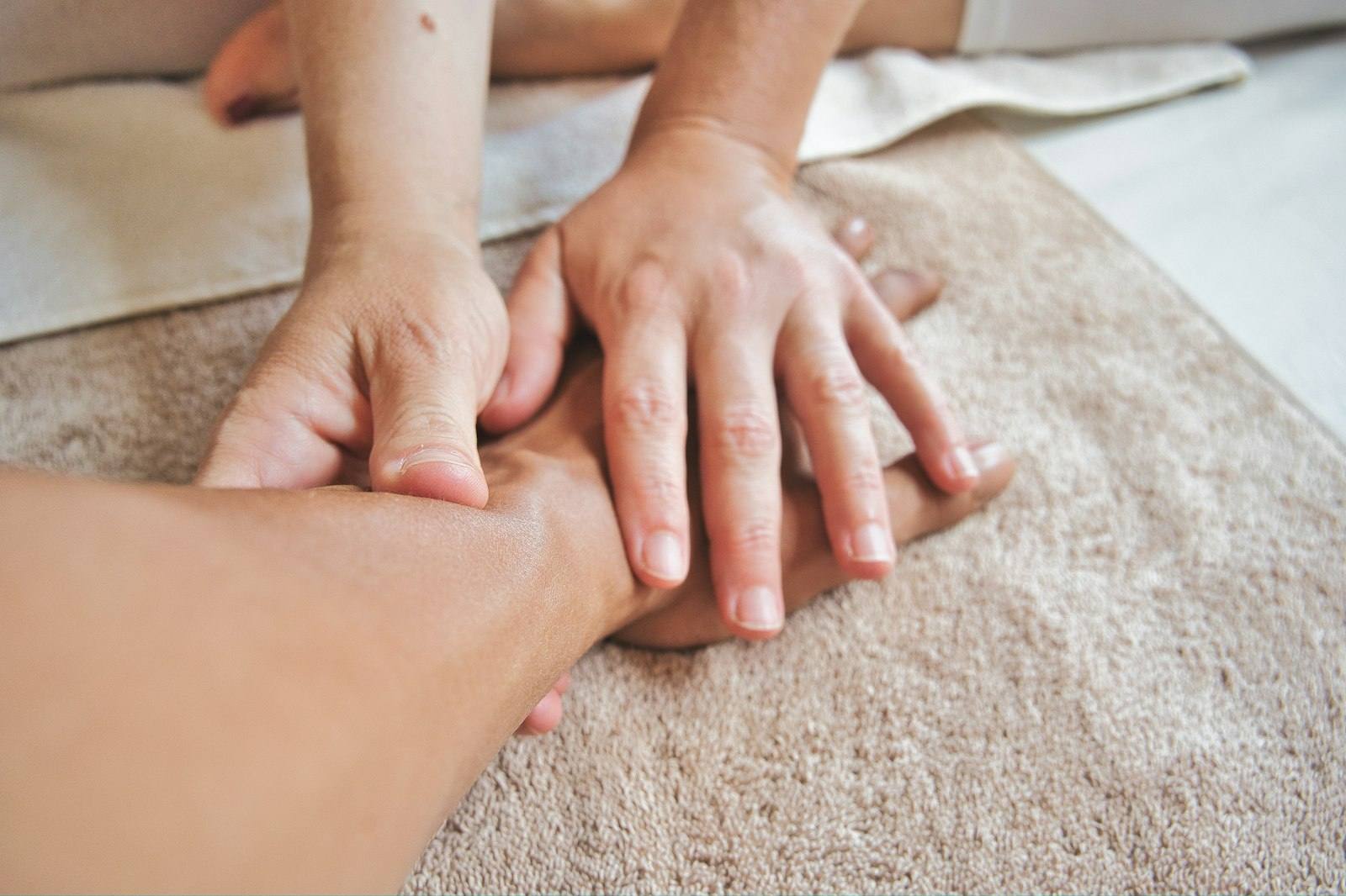 Therapist’s hands working gently along a client’s forearm